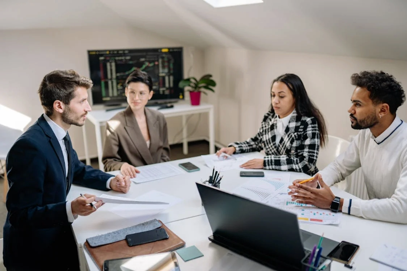 group of people of different races discussing work at a desk, representing diversity and inclusion in recruitment.