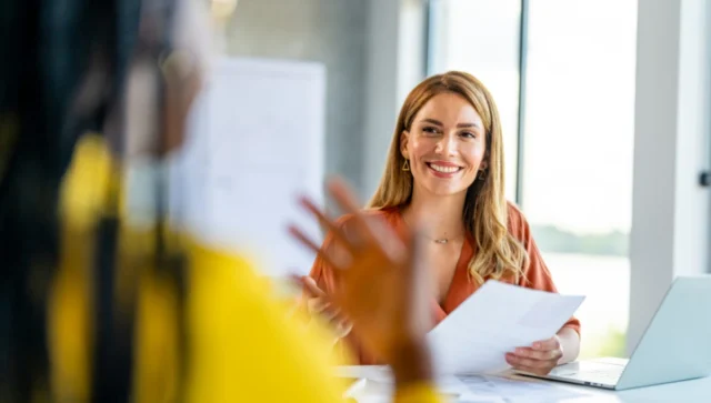woman behind a desk smiling at another woman